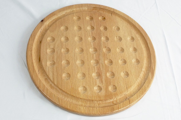 A close-up of the marble solitaire game without the marbles.