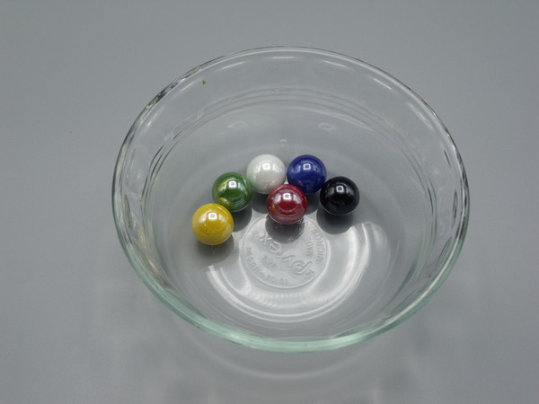 A clear glass bowl with one marble of each of the six colors.