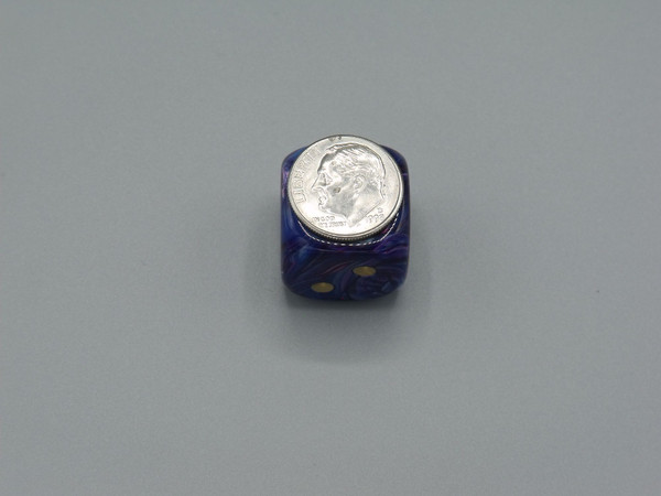 One die with a dime on one for scale.