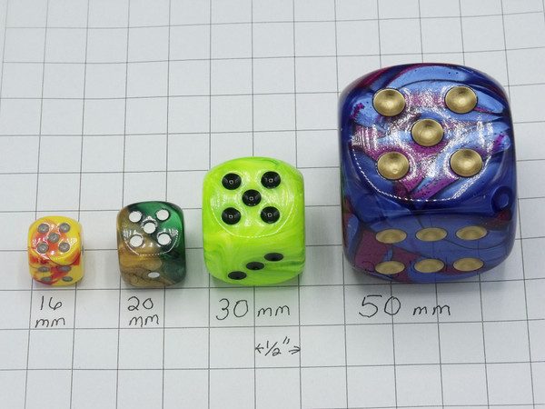 Four dice on graph paper showing the different sizes:  16mm, 20mm, 30mm, and 50 mm.