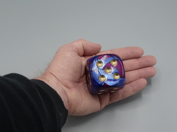 A 50mm die in an adult's hand.