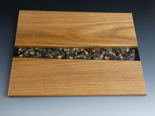 Oak River Pour Serving Board #16
This river pour style charcuterie serving board has solid oak on both sides and smooth stones set in clear epoxy in the center. 
 
The charcuterie board is about 11"wide, 14"long, and 5/8" thick.