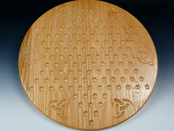 A Chinese checkers board in oak with celtic designs between the points.
