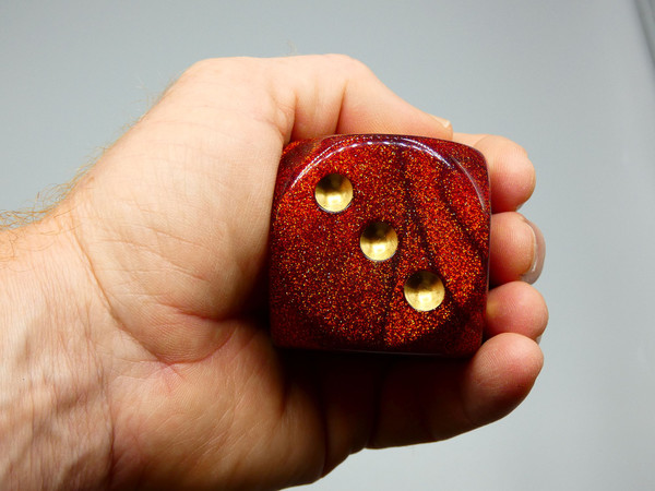 A 50mm dice in an adult's hand.