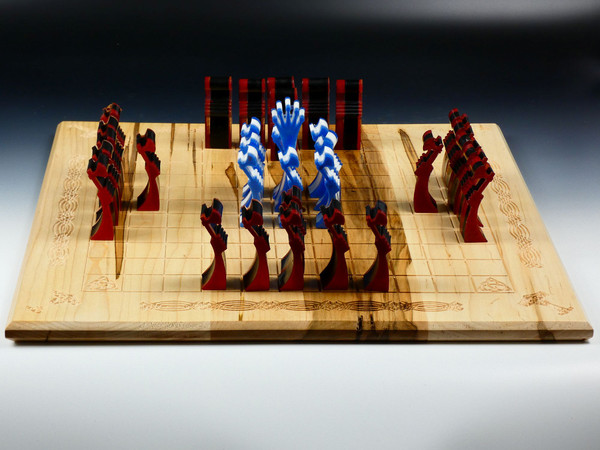 Hnefatafl board with the poured resin pieces in their starting positions.  The resin pieces are either white with blue or black with red.