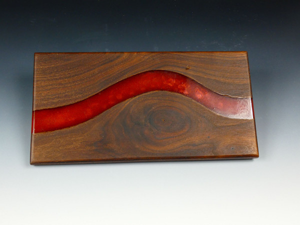A walnut serving board with  red epoxy resin going through it.