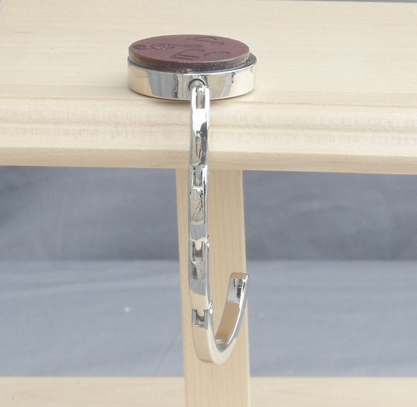 An open purse hook hanging off the edge of a table.