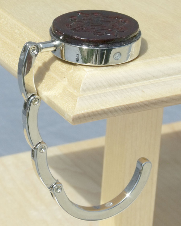 An open purse hook hanging off the edge of a table.