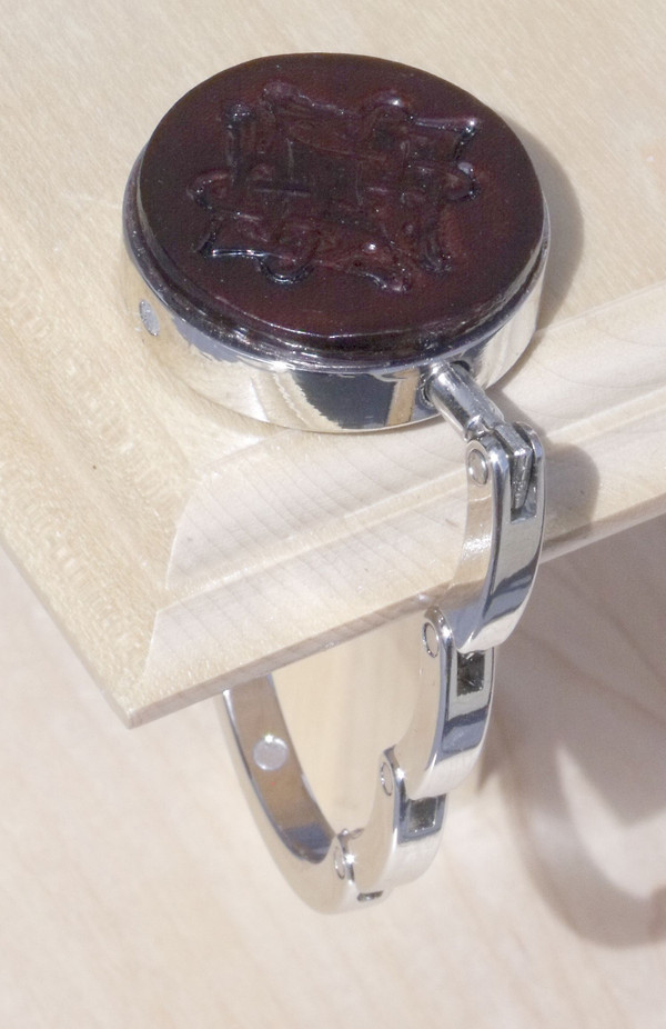 An open purse hook hanging off the edge of a table.