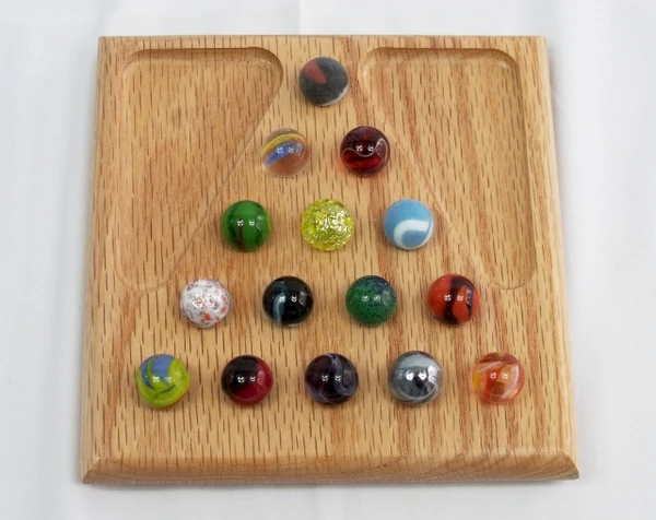 A small marble solitaire game in oak with the marbles in their starting positions.