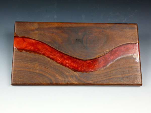 A walnut serving board with  red epoxy resin going through it.  The red is from red colored mica powder so it is not a solid red but has some swirls in it.