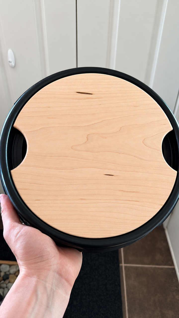Maple Barrel Buddy hardwood cutting board fitted in a blue camping barrel lid
