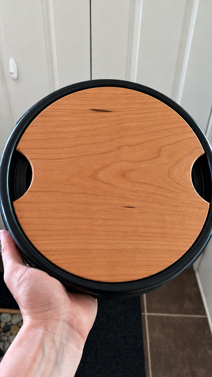 Cherry Barrel Buddy hardwood cutting board fitted in a blue camping barrel lid