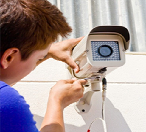 Always Affordable Locksmiths technician installing a security camera on an exterior wall in Calgary