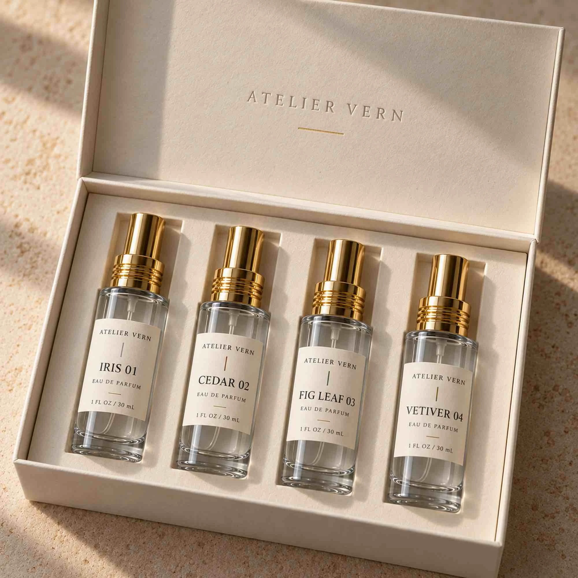 Perfume discovery set of four 1 oz cylindrical glass bottles with gold sprayers in a fitted gift box
