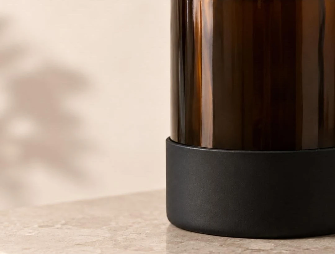 Silicone boots on glass bath and body bottles — soft-touch grip and cushioning on stone and ceramic surfaces