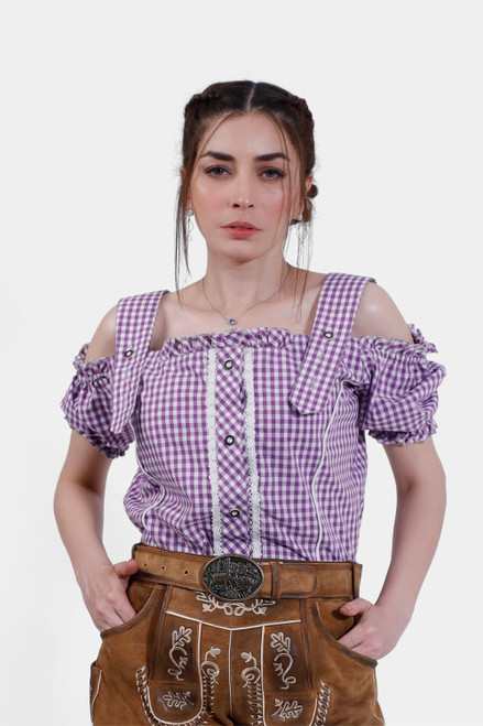 Woman wearing the Rihanna Traditional Blouse in purple checkered pattern, front view. The blouse features off-the-shoulder sleeves with ruffled edges and lace detailing along the buttons, paired with traditional leather trousers. The blouse showcases intr