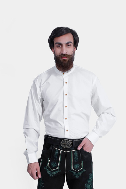 A man wearing the Ryan Lederhosen Shirt, a traditional white long-sleeve shirt with a mandarin collar and wooden buttons. He pairs it with black leather Lederhosen adorned with green embroidery and a decorative belt buckle. This ensemble is ideal for Okto
