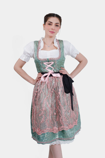 Young woman in Dirndl Nilam with mint green bodice, pink lace-up detailing, and floral patterned skirt, posing with hand on hip. dirndl grün, dirndl grün pink