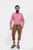 A man wearing traditional Bavarian clothing stands against a plain white background. He is dressed in a red and white checkered shirt paired with brown leather Bundhosen that extend just below the knee. He has a thick beard and a serious expression. His o