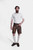 full-body view of the man showing the white shirt and brown lederhosen paired with cream-colored knee-high socks and brown shoes.