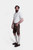 A front side view of the man wearing the brown leather lederhosen with suspenders, paired with the white shirt.