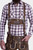 A man wearing traditional Bavarian Lederhosen. He is dressed in a checkered long-sleeve shirt with shades of brown and white, paired with brown leather shorts that have intricate white embroidery and suspenders.