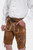 Close-up view of the brown lederhosen, showcasing the detailed embroidery on the front and sides. The man is wearing a white dress shirt and has his right hand in his pocket.
