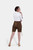 A rear view of a woman wearing earthy brown lederhosen with a white shirt, showcasing the back design of the lederhosen, paired with beige heels.