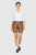 A woman wearing a white button-down shirt with lace details on the sleeves, paired with brown embroidered Lederhosen shorts. The shorts feature floral embroidery and decorative buttons, complemented by white socks and brown shoes with buckles.