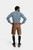 Back view of a man in a Lars Eidinger Lederhosen outfit, showing the rear details of the tan leather shorts and the fit of the green checkered shirt.