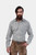 A bearded man wearing the André Lederhosen Shirt, featuring a green and white checkered pattern. He is paired with traditional beige lederhosen embroidered with green detailing. The man stands confidently with one hand in his pocket against a plain white 
