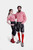 The couple posing in their Bamberger Couple Outfits. The woman has her arm around the man's shoulder, showcasing her red checkered off-shoulder blouse and embroidered black knee-length lederhosen. The man complements her look with a matching red checkered
