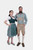 A man and woman in traditional Bavarian attire. The woman is wearing a green dirndl dress with a white blouse, while the man is dressed in beige lederhosen with green embroidery and a green checkered shirt. Both stand confidently, showcasing their stylish