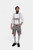 A man wearing traditional Bavarian Lederhosen. He is dressed in a white dress shirt with a black bow tie and light gray leather shorts adorned with intricate black embroidery and suspenders. He completes the outfit with light gray knee-high socks and blac