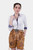 A woman wearing Diane Kruger Lederhosen in Caramel Desert color, paired with a white blouse, posing confidently.