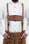 Close-up of a man wearing Tegernsee Bundhosen with suspenders. The focus is on the white traditional shirt and the detailed brown bundhosen with ornate embroidery and suspenders.