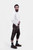 A side profile of a man showcasing Monte Carlo Bundhosen paired with a white button-down shirt. The Bundhosen, made of dark brown leather, feature intricate embroidery and a decorative belt buckle. Paring with traditional socks and brown shoes 