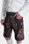 Side view of a model wearing Spiegel Lederhosen, emphasizing the detailed embroidery on the side of the leather shorts and the elegant belt buckle, paired with a white shirt.