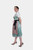 Model wearing the Dirndl Nilam, featuring a light blue bodice with floral patterns, a matching skirt, and a white blouse, styled with a blue apron.
