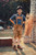 A young boy stands outdoors wearing Jakob Jäger Lederhosen, featuring a rustic amber color and traditional Bavarian design, with suspenders and detailed embroidery. He pairs the lederhosen with a blue plaid shirt and brown shoes, posing confidently with hands on his hips in a charming, rustic garden setting. kinderlederhose