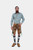 A man in a green checkered shirt and brown lederhosen with intricate embroidery, standing with a confident expression and one hand in his pocket. braune lederhose​, lederhose braun