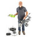 Person carrying a folded TravelScoot Escape frame in one hand and its battery in the other, with removed components on the floor.