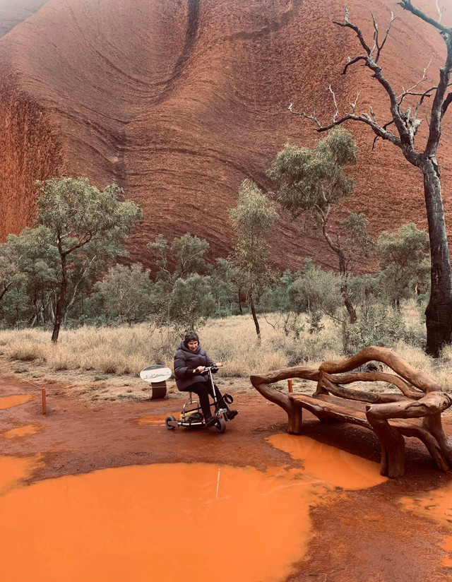 Woman riding a TravelScoot Escape on wet uneven terrain