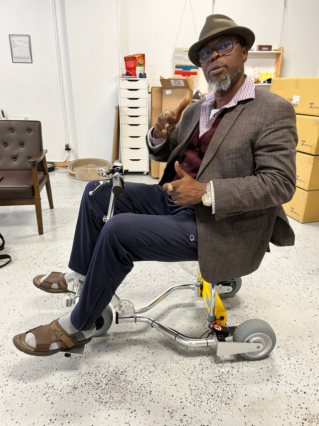 Six-foot-three-inch man seated on a TravelScoot Escape