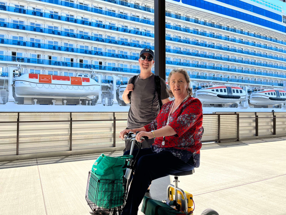 TravelScoot owners beside an Escape in front of a cruise ship