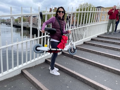woman holding unfolded ultra-lightweight mobility scooter