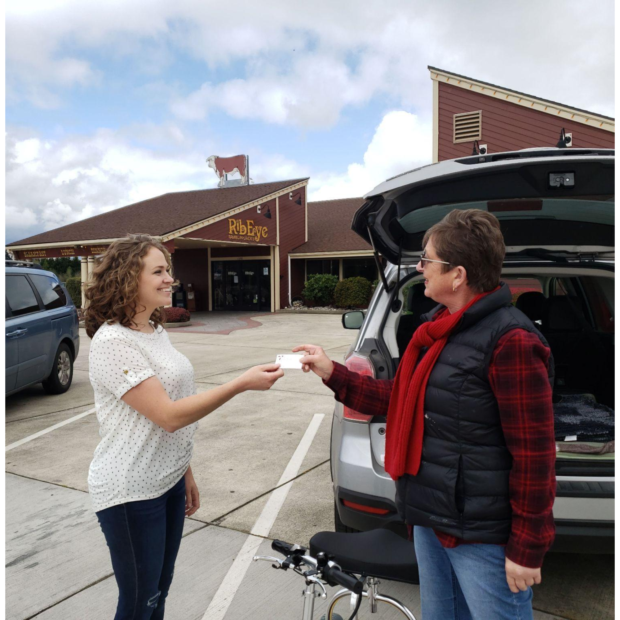 Woman handing out a referral card to another woman.