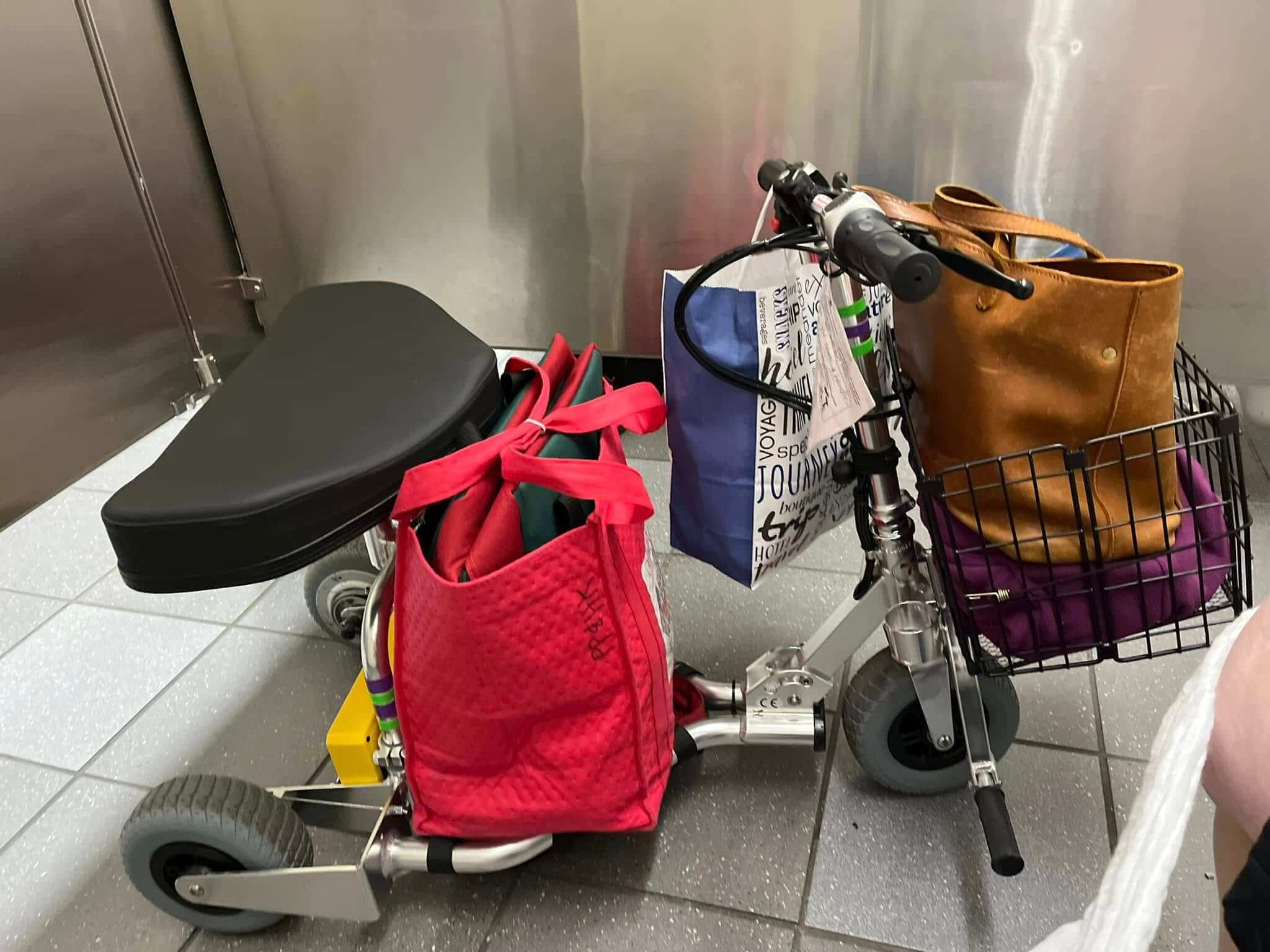 Mobility scooter with a lot of luggage stacked on top of it.