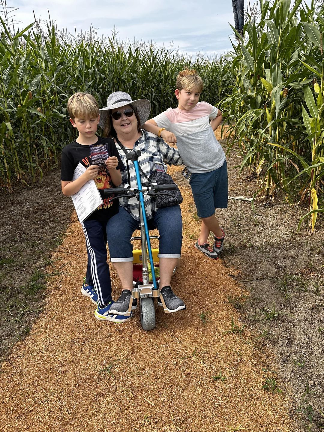 Woman with two children in a cornfield on a travel scooter.